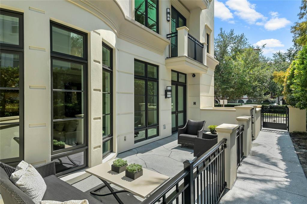 A patio with outdoor furniture and a black metal railing sits beside a modern building — 125 S INTERLACHEN AVENUE UNIT 1, WINTER PARK, FL