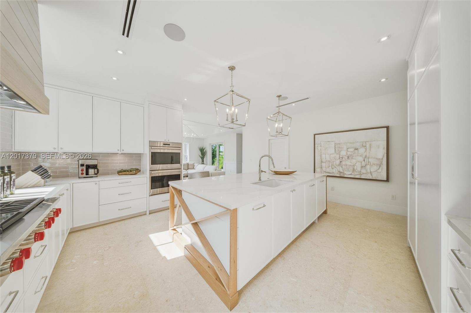 A modern white kitchen features a large center island with wood accents and stone countertops — 75840 Overseas Highway, Islamorada FL 33036, ISLAMORADA, FL