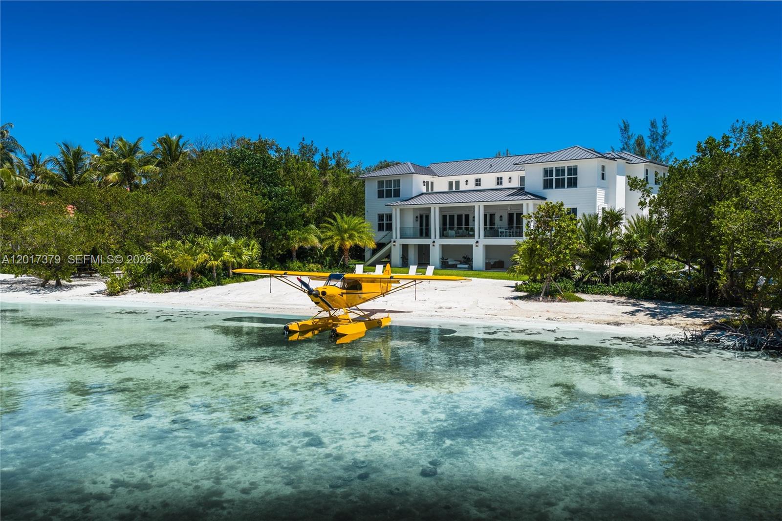 A yellow seaplane is parked on a sandy beach in front of a white house — 75840 Overseas Highway, Islamorada FL 33036, ISLAMORADA, FL