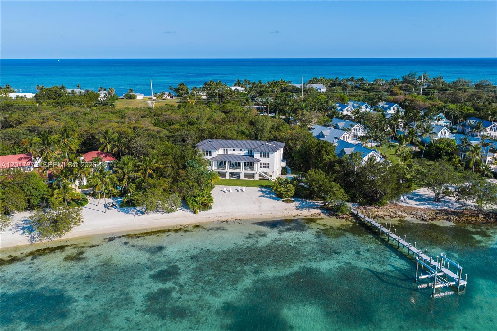 An aerial view shows a large white house on a sandy beach with a dock — 75840 Overseas Highway, Islamorada FL 33036, ISLAMORADA, FL
