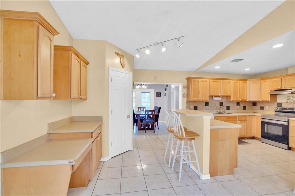 A kitchen with light wood cabinets, tile flooring, and a breakfast bar with two stools — SEBASTIAN, FL