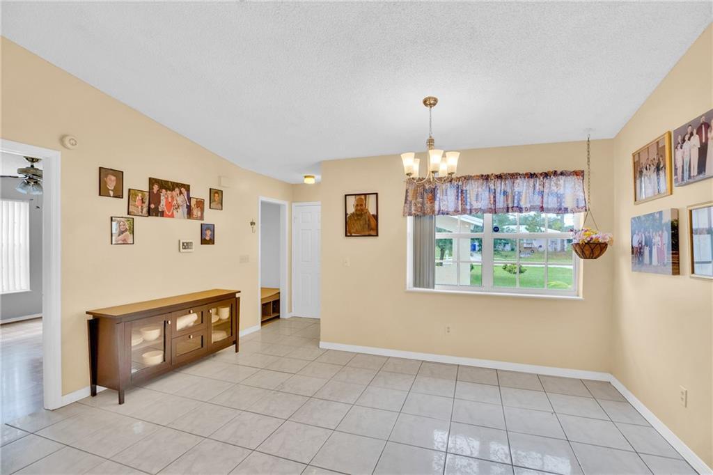 A dining room with light-colored walls, tile flooring, a chandelier, and a large window — SEBASTIAN, FL