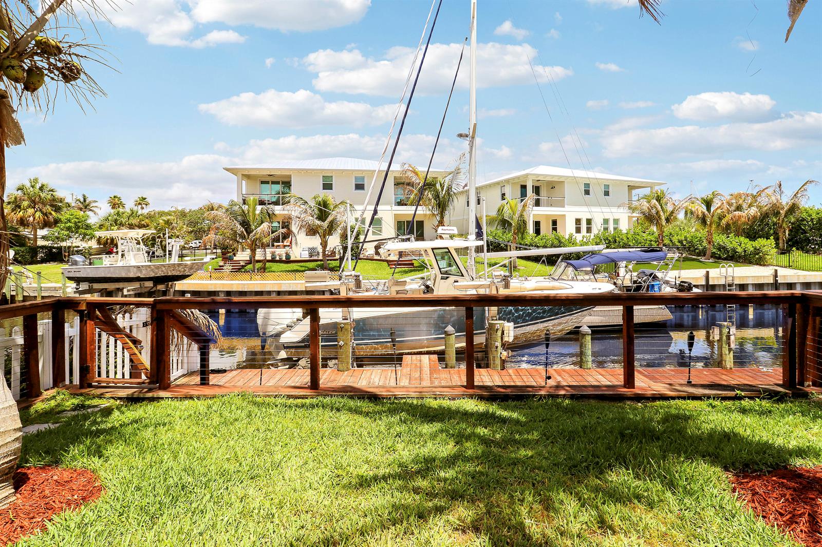 A wooden deck overlooks a canal with two boats docked in front of two houses — 3997 SE Barcelona Street, Stuart FL 34997, STUART, FL
