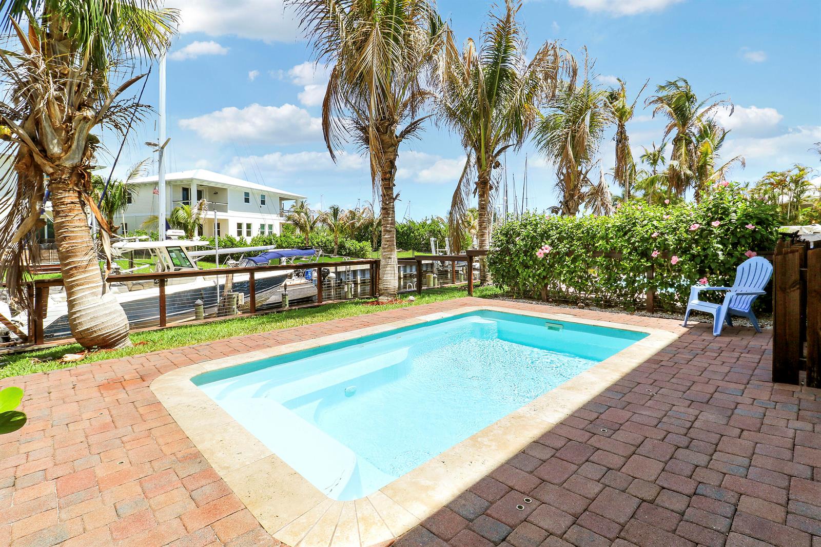 A rectangular swimming pool sits on a brick patio next to palm trees and boats — 3997 SE Barcelona Street, Stuart FL 34997, STUART, FL