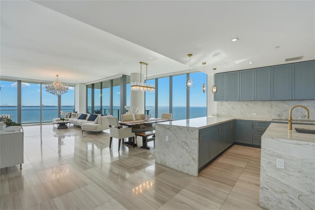 An open-concept kitchen and living area features marble countertops, blue cabinetry, and floor-to-ceiling windows — 3101 BAYSHORE BOULEVARD UNIT 504, TAMPA, FL