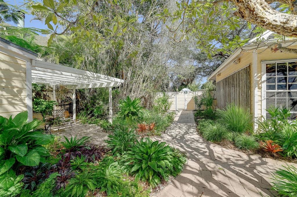 A stone pathway leads through a lush garden between two yellow buildings with a pergola — 226 OGDEN STREET, SARASOTA, FL
