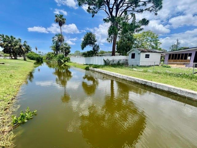 A canal flows past a grassy yard with a white fence and a small shed — 5113 AVERY ROAD, NEW PORT RICHEY, FL