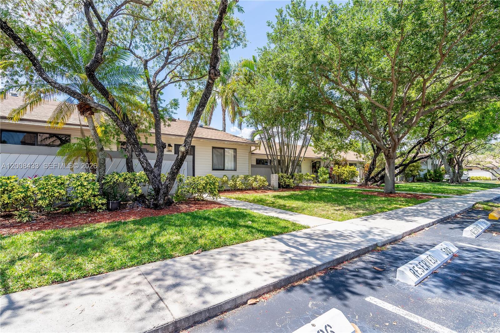 A single-story residential building with light-colored siding is surrounded by mature trees and landscaping — 9804 NW 37th St # 3E, Sunrise FL 33351, SUNRISE, FL
