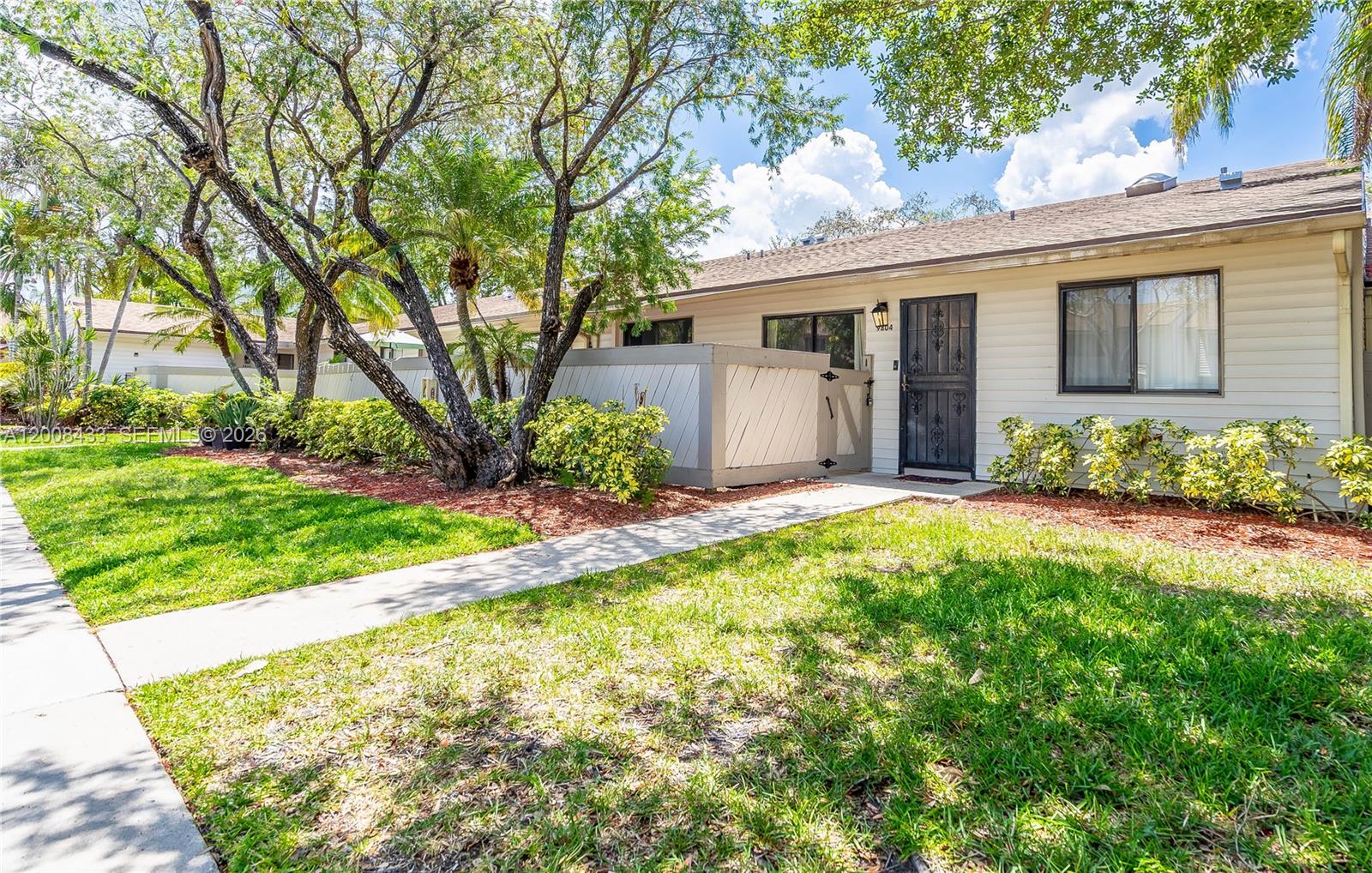 A single-story residential building with a concrete walkway, a fenced patio, and mature trees — 9804 NW 37th St # 3E, Sunrise FL 33351, SUNRISE, FL