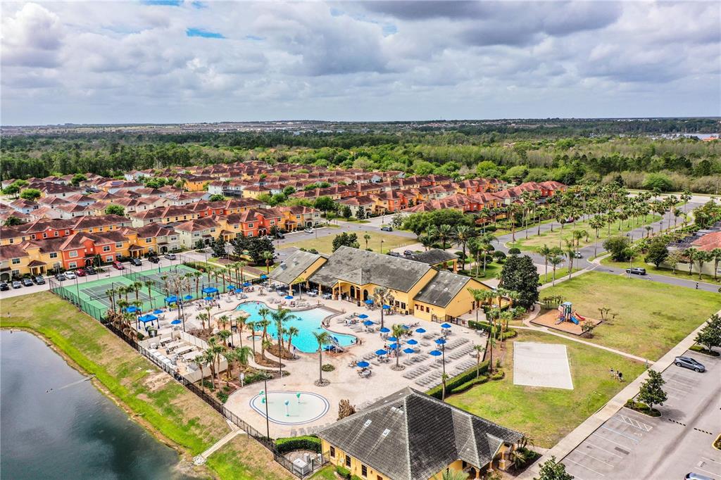 An aerial view shows a community clubhouse with a swimming pool, tennis courts, and housing — 8972 CALIFORNIA PALM ROAD, KISSIMMEE, FL