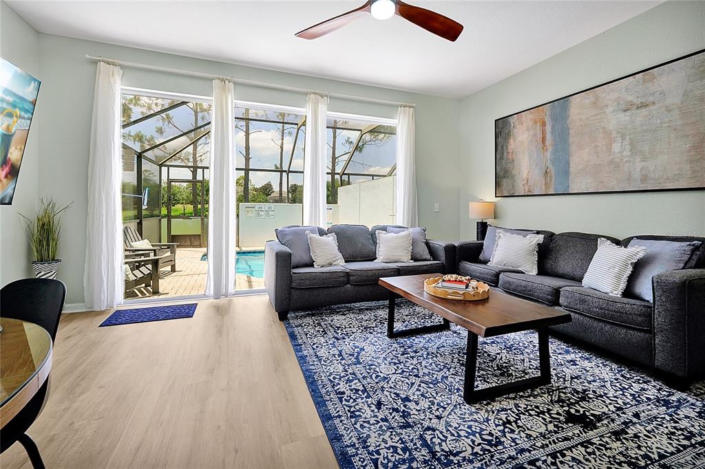 A living room features a dark sofa, a blue patterned rug, and sliding glass doors — 2500 RENSHAW STREET, KISSIMMEE, FL