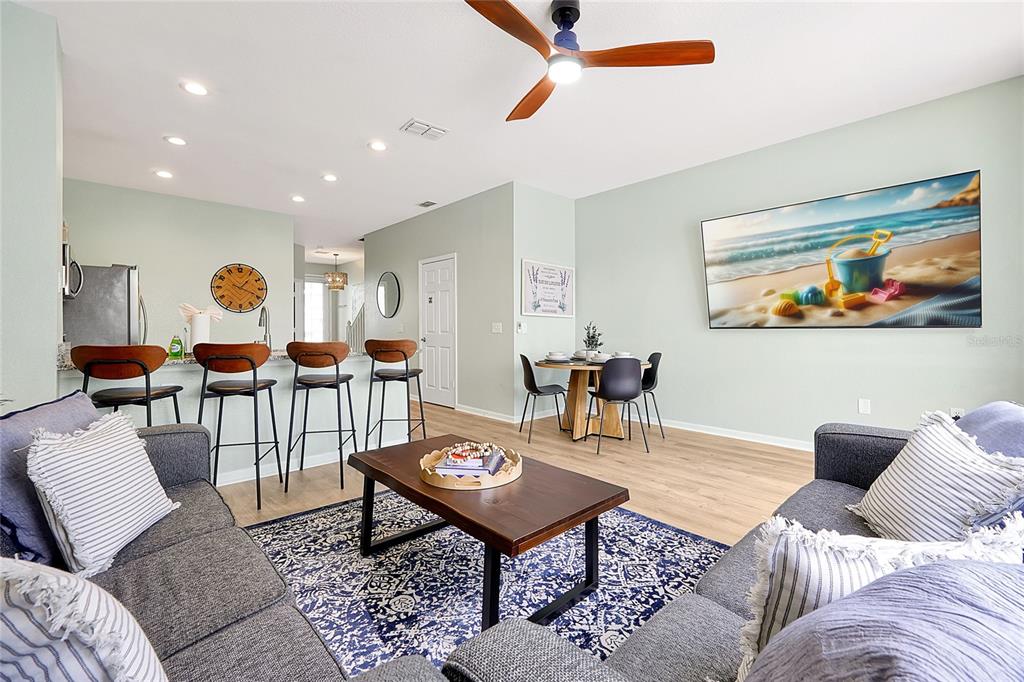 An open-concept living and dining area features a kitchen island, wood flooring, and ceiling fan — 2500 RENSHAW STREET, KISSIMMEE, FL