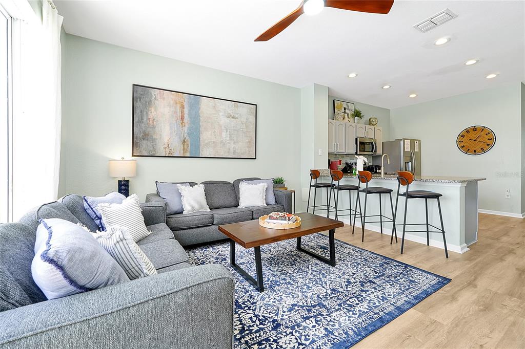 A living room with a gray sofa, coffee table, and an open kitchen with bar stools — 2500 RENSHAW STREET, KISSIMMEE, FL