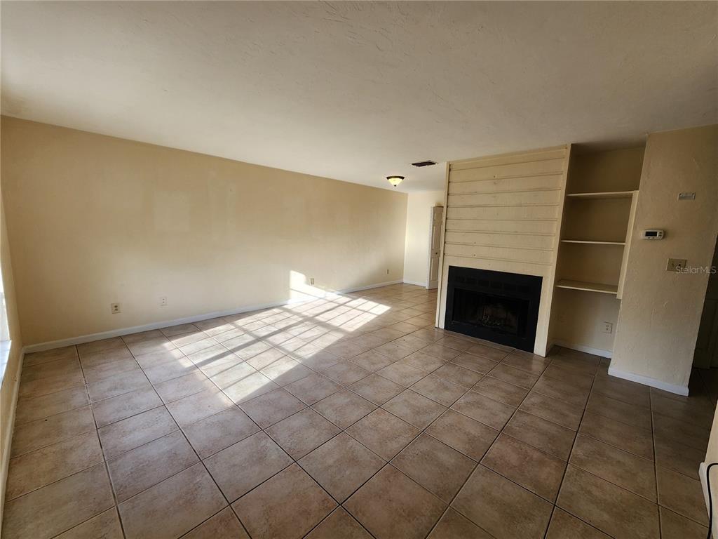 A living room features beige tile flooring, a fireplace with wood paneling, and built-in shelves — 2529 NW 62 PLACE, GAINESVILLE, FL