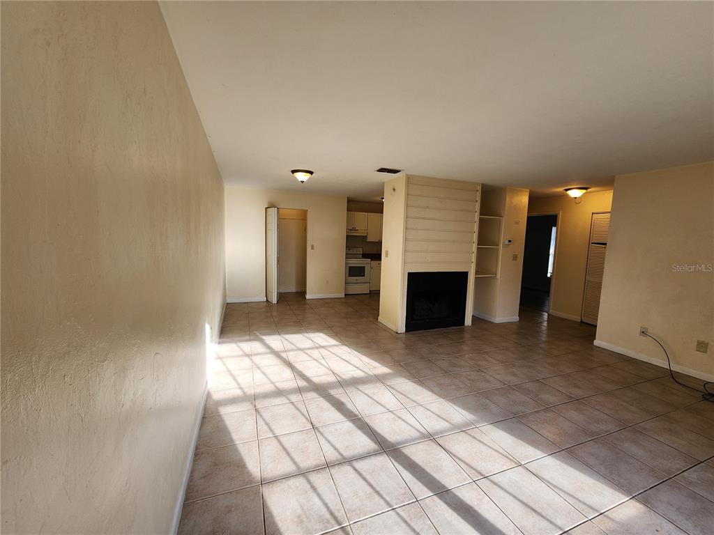 A living room with tile flooring, a fireplace, and an open view into the kitchen — 2529 NW 62 PLACE, GAINESVILLE, FL