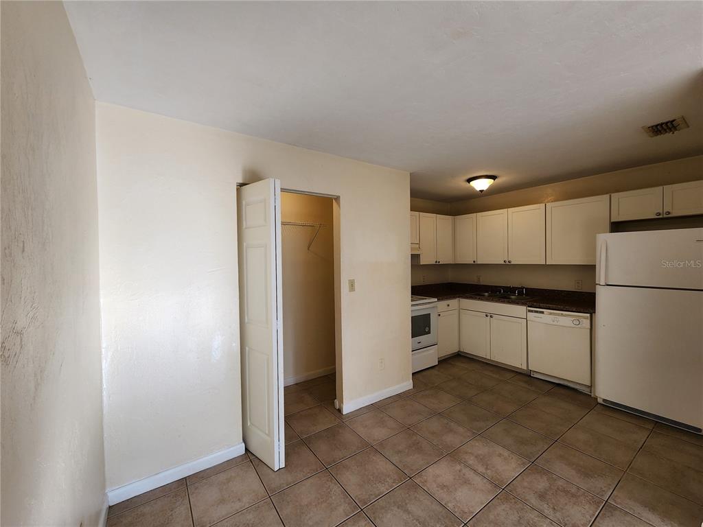 A kitchen with white cabinets, tile flooring, and an adjacent closet with an open door — 2529 NW 62 PLACE, GAINESVILLE, FL