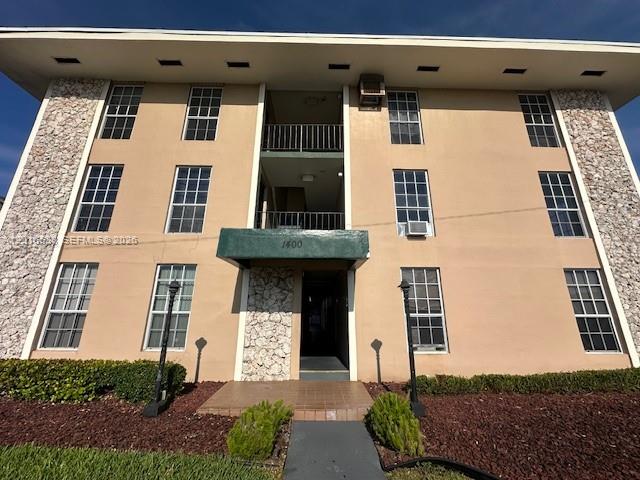 A three-story apartment building features a tan stucco facade, stone accents, and a central entrance — 1400 S Douglas Rd # 14, Coral Gables FL 33134, CORAL GABLES, FL
