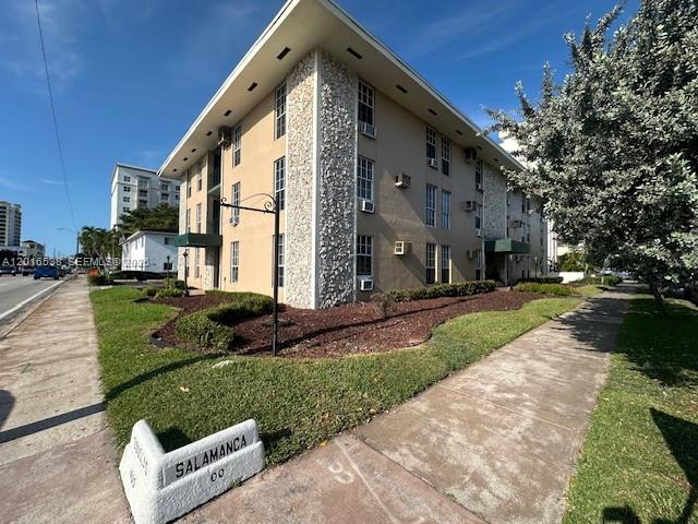 A multi-story apartment building with a stone facade stands next to a sidewalk — 1400 S Douglas Rd # 14, Coral Gables FL 33134, CORAL GABLES, FL