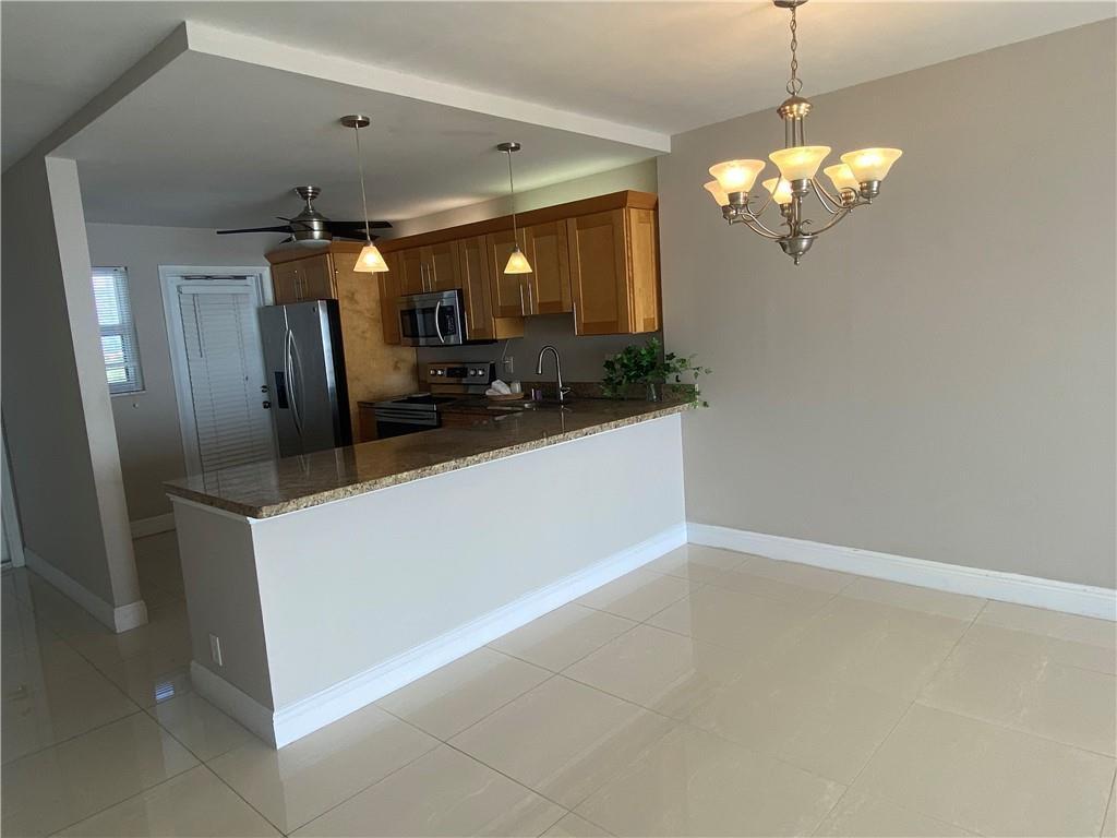 An elevated view of a sandy beach, ocean, and palm trees from a balcony — 750 N Ocean Boulevard # 1009, Pompano Beach FL 33062, POMPANO BEACH, FL