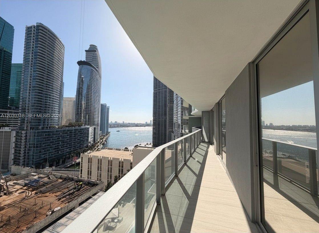 A balcony with a glass railing overlooks a bay and city skyline — 77 SE 5th St # 1903, Miami FL 33131, MIAMI, FL