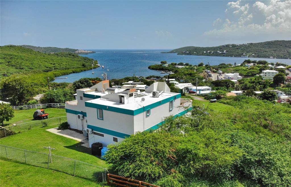 An elevated exterior view of a white house with teal trim overlooking a coastal bay — 250 LAS DELICIAS, CULEBRA, PR