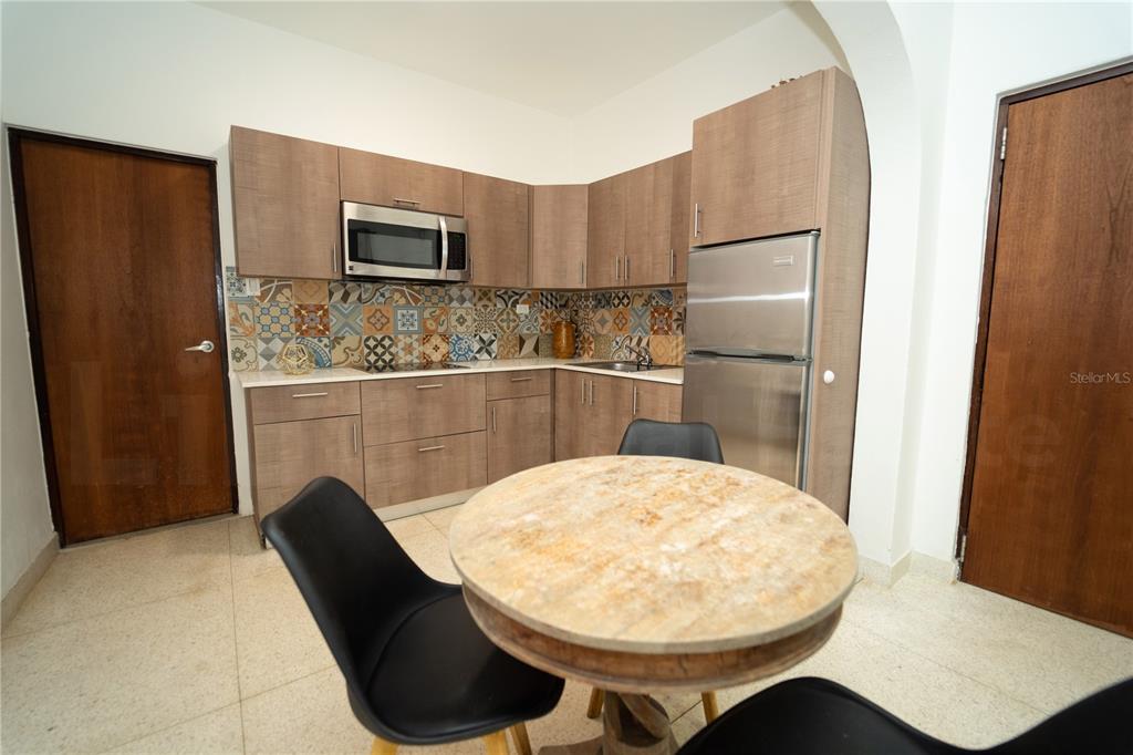 A kitchen features wood-tone cabinets, a patterned tile backsplash, stainless steel appliances, and a table — 2019 CACIQUE STREET, SAN JUAN, PR