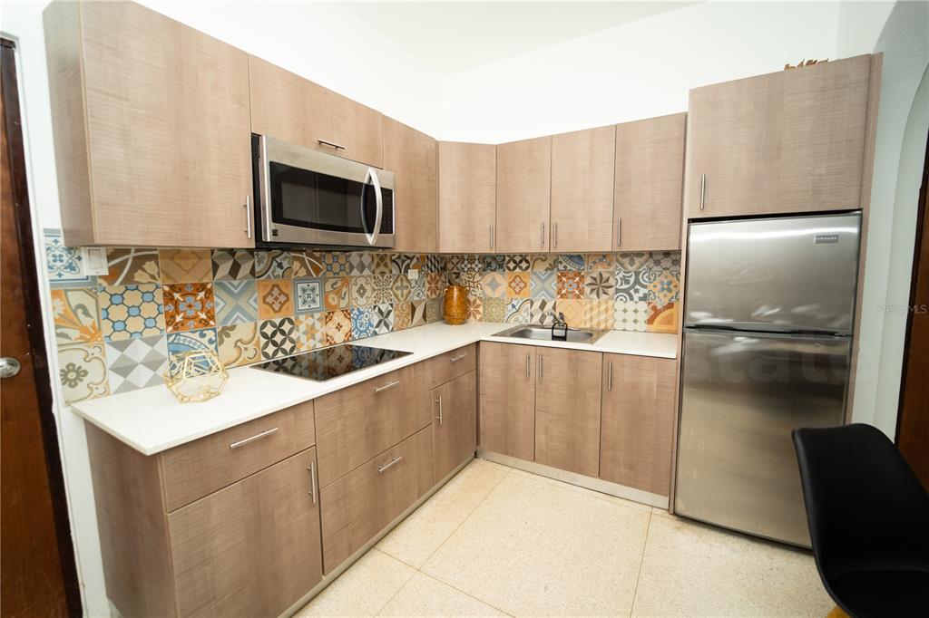 A kitchen features light wood cabinets, stainless steel appliances, and a colorful patterned tile backsplash — 2019 CACIQUE STREET, SAN JUAN, PR