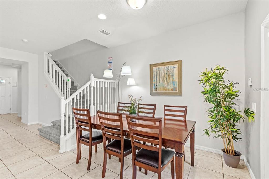 A dining area with a wooden table, four chairs, a floor lamp, and a staircase — 2015 MAJORCA DRIVE, KISSIMMEE, FL
