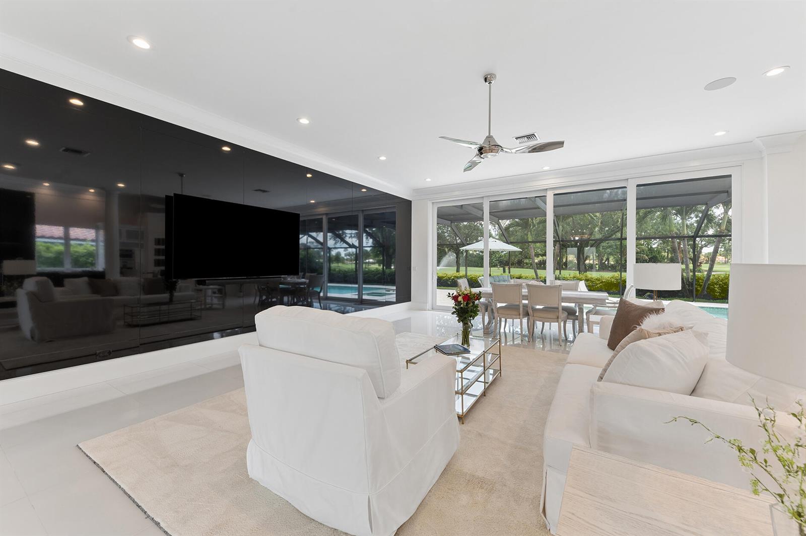A bright open-concept living room features white tile floors, a large rug, and sliding doors — 11938 N Lake Drive, Boynton Beach FL 33436, BOYNTON BEACH, FL
