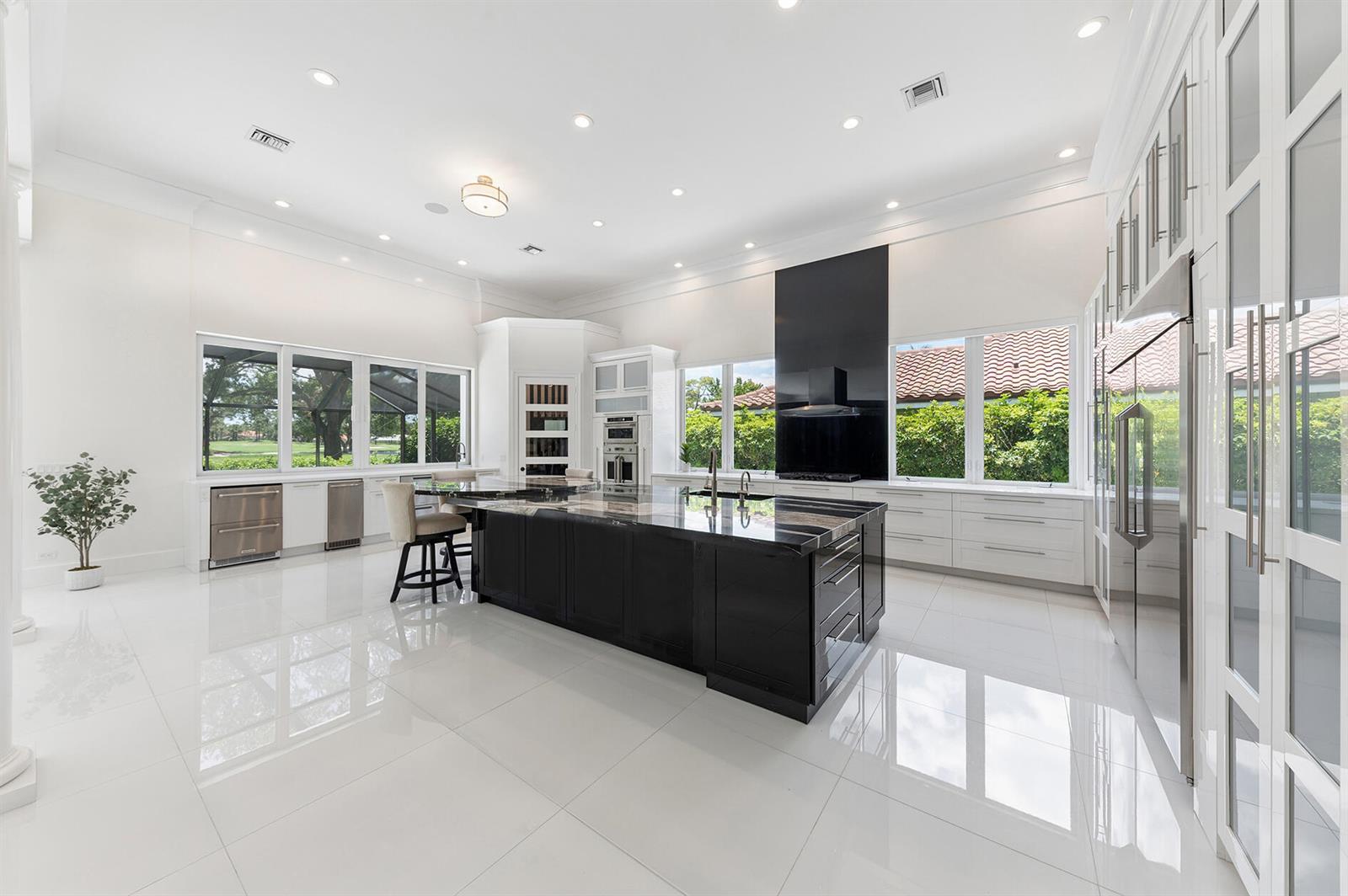 A bright, open-concept living and dining area features white tile floors, columns, and a staircase — 11938 N Lake Drive, Boynton Beach FL 33436, BOYNTON BEACH, FL