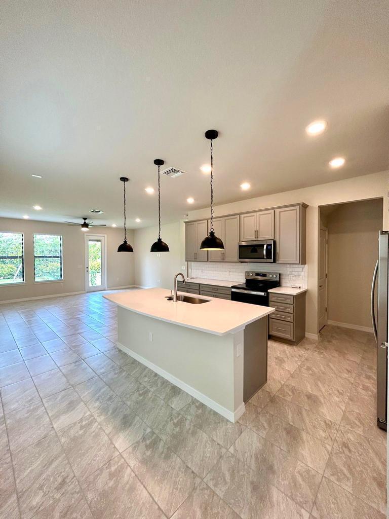 A kitchen with a central island, grey cabinets, stainless steel appliances, and tile flooring — 4845 Chantilly Road, Lake Worth FL 33467, LAKE WORTH, FL