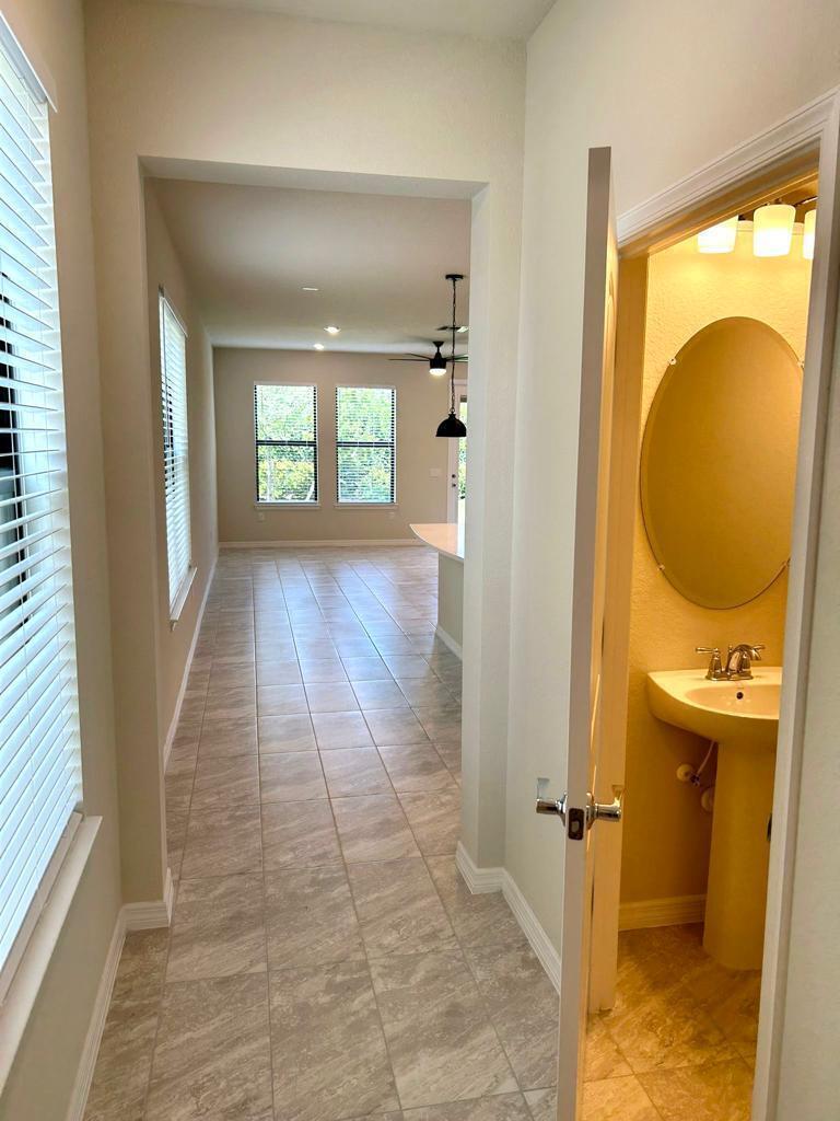 A hallway with tile flooring leads toward a kitchen area, with a powder room adjacent — 4845 Chantilly Road, Lake Worth FL 33467, LAKE WORTH, FL
