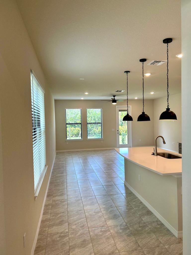 A kitchen island with pendant lights overlooks an open living area with tile flooring — 4845 Chantilly Road, Lake Worth FL 33467, LAKE WORTH, FL