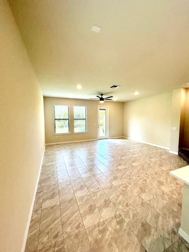 An empty living room features beige walls, tile flooring, a ceiling fan, and large windows — 4845 Chantilly Road, Lake Worth FL 33467, LAKE WORTH, FL
