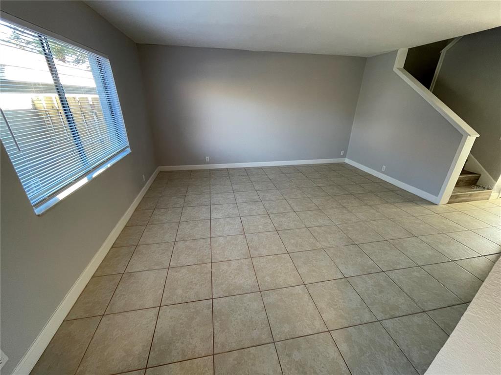 An empty living room features light gray walls, large square floor tiles, and a staircase — 3307 KILMER DRIVE UNIT 3307, LAKELAND, FL