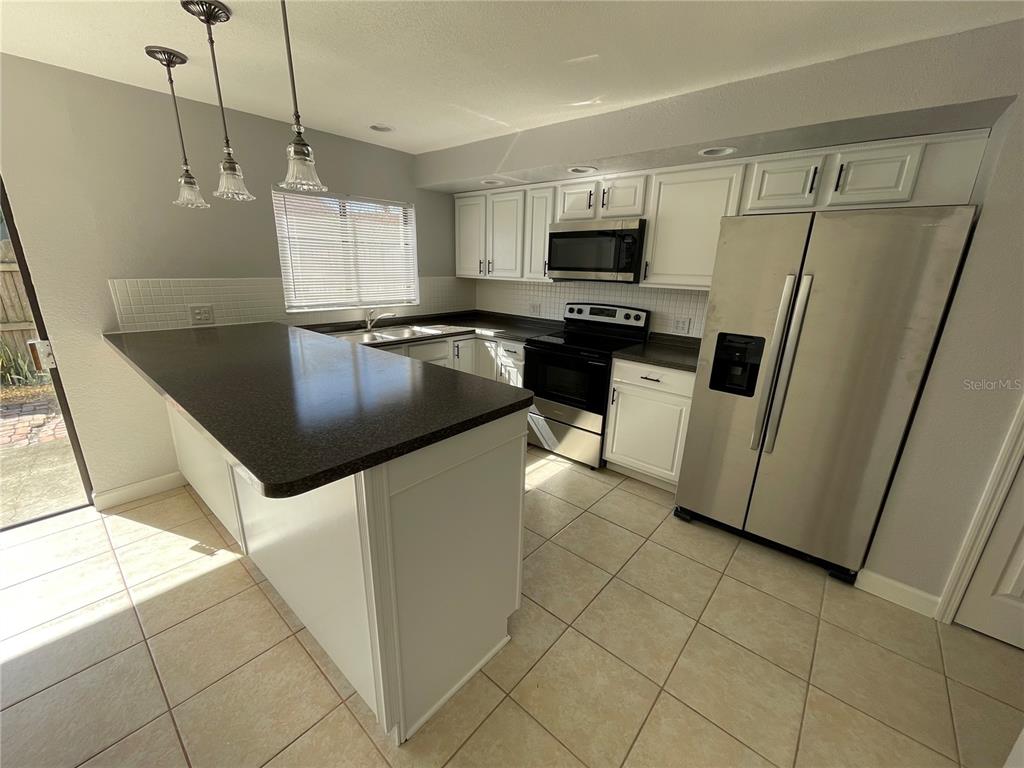 A kitchen features white cabinets, stainless steel appliances, a dark countertop, and tile flooring — 3307 KILMER DRIVE UNIT 3307, LAKELAND, FL
