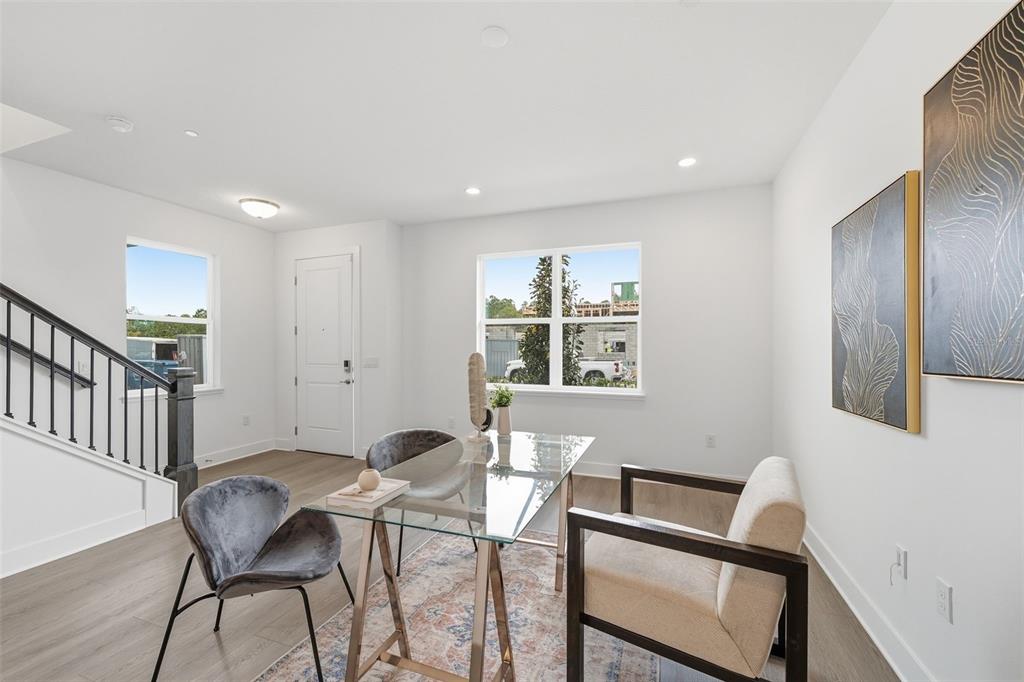 A home office features a glass desk, two chairs, wood-look flooring, and two wall art pieces — 9156 SINATRA LANE, ORLANDO, FL
