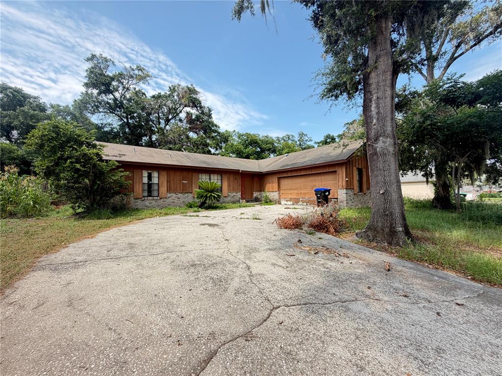 A single-story house with wood siding, a brick base, and a cracked concrete driveway — 6234 SPARLING HILLS CIRCLE, ORLANDO, FL