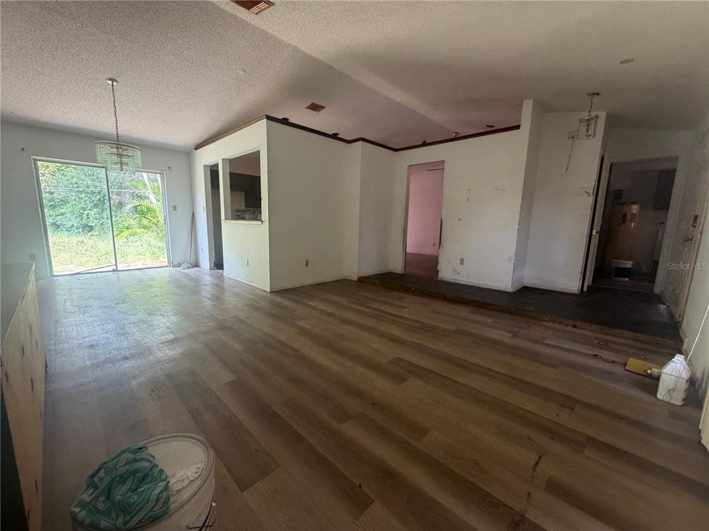 An open-concept living area features wood-look flooring, white walls, and a sliding glass door — 6234 SPARLING HILLS CIRCLE, ORLANDO, FL