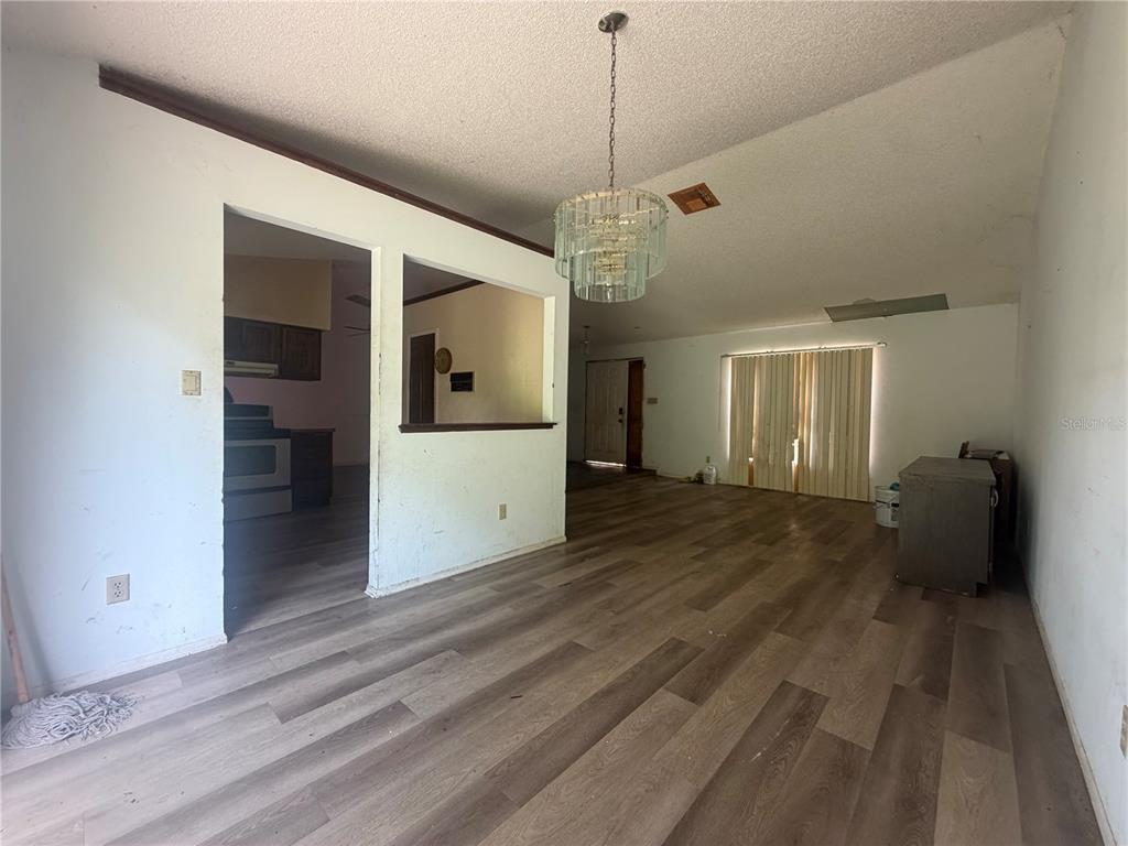 An open-concept living and dining area features wood-look flooring, a crystal chandelier, and a pass-through — 6234 SPARLING HILLS CIRCLE, ORLANDO, FL