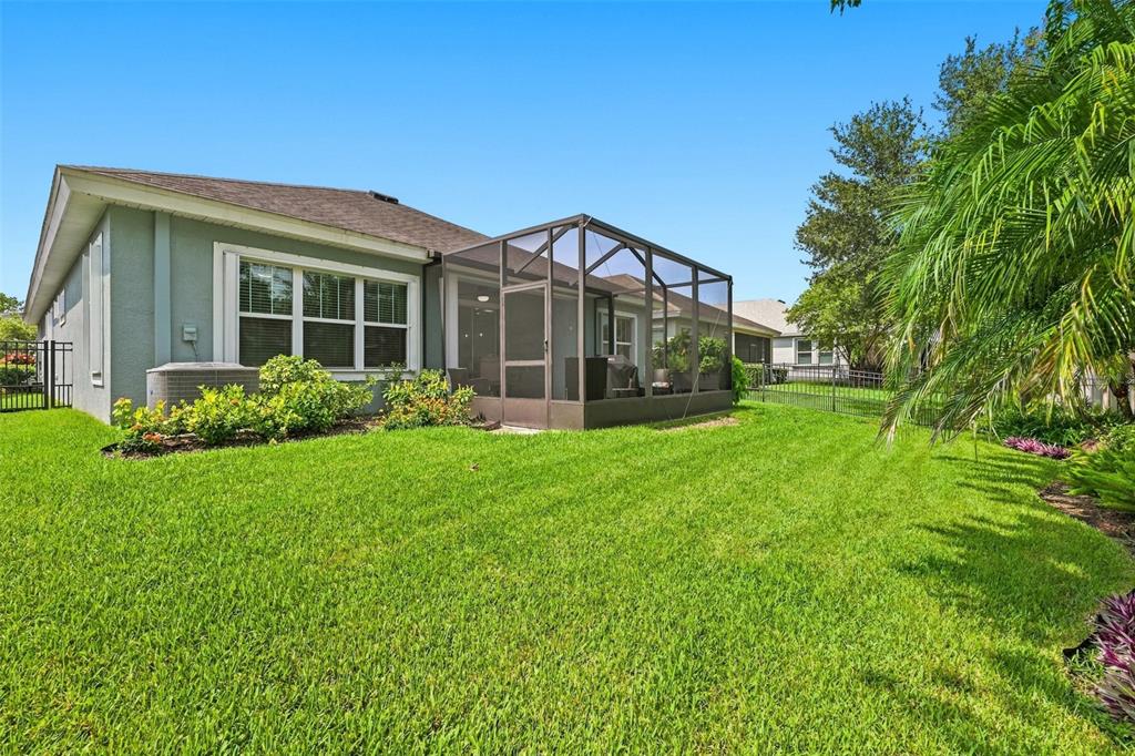 A backyard view of a house with a screened-in patio and a green lawn — 6517 NESTALL COURT, APOLLO BEACH, FL