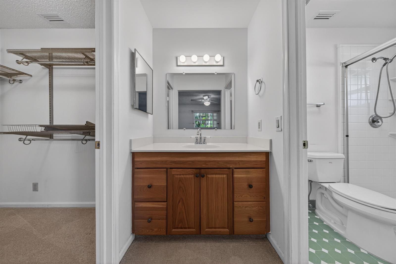 A bathroom vanity with a wooden cabinet sits between a walk-in closet and a bathroom — 4234 NW 3rd Way, Boca Raton FL 33431, BOCA RATON, FL