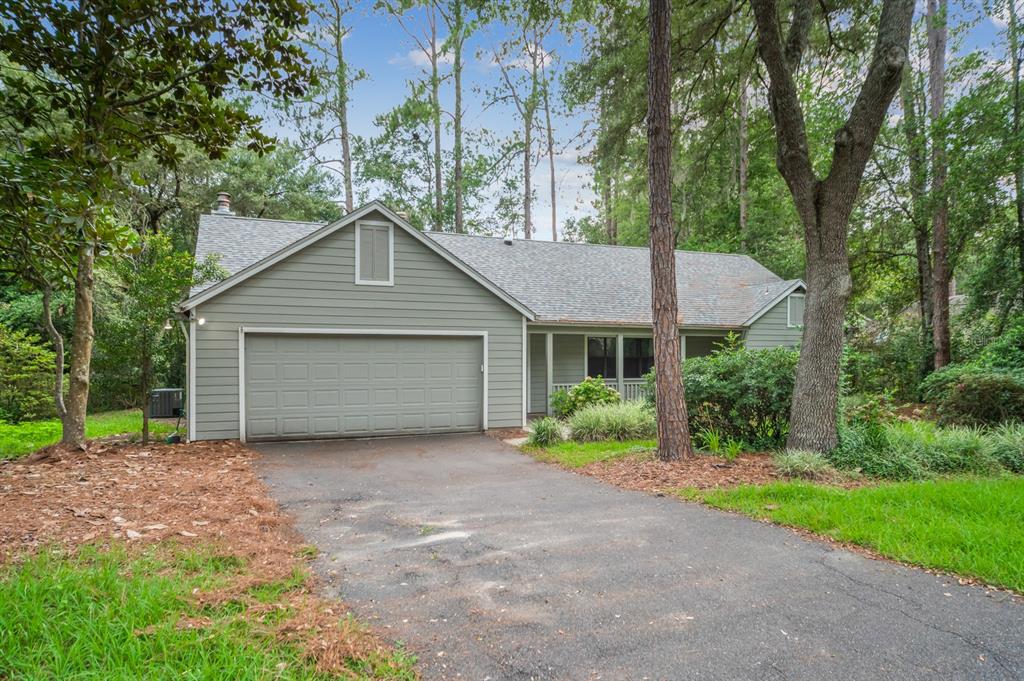A single-story house with light green siding, a two-car garage, and a paved driveway — 8025 SW 47TH COURT, GAINESVILLE, FL