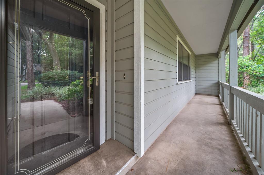 A covered porch with light green siding, a glass storm door, and a wooden railing — 8025 SW 47TH COURT, GAINESVILLE, FL