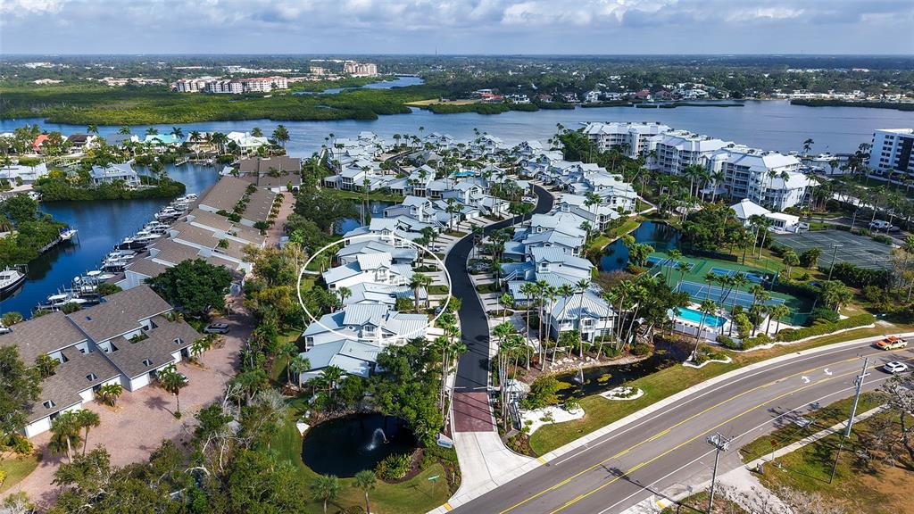 An aerial view shows a residential community with white buildings, a pond, and tennis courts — 1225 SIESTA BAYSIDE DRIVE UNIT 1225B, SARASOTA, FL