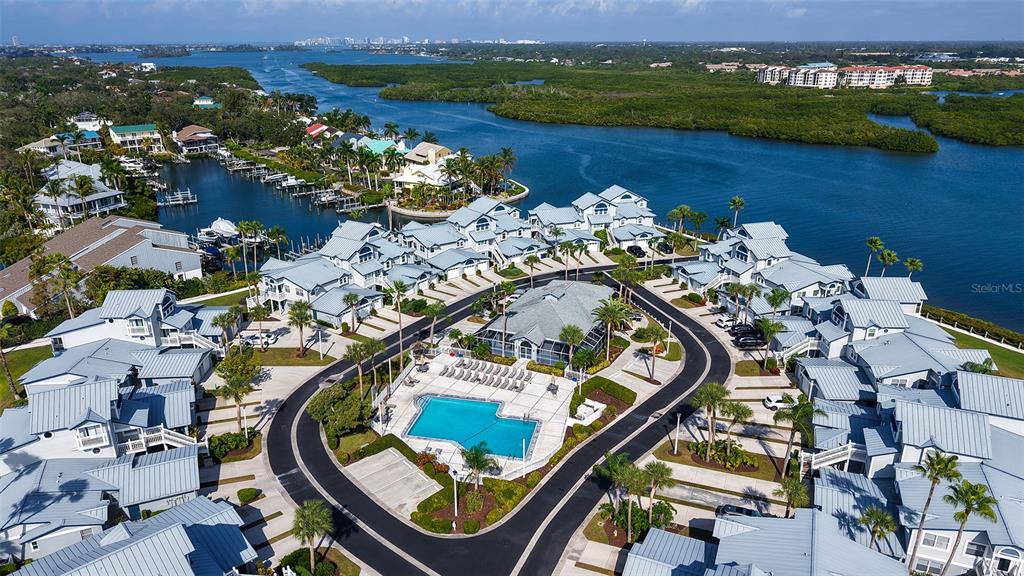 An aerial view shows a residential complex with a central pool and surrounding waterfront homes — 1225 SIESTA BAYSIDE DRIVE UNIT 1225B, SARASOTA, FL