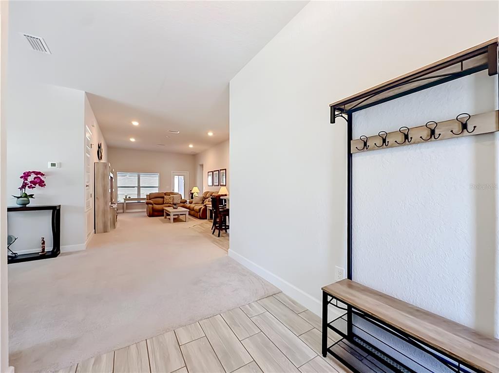 An entryway with a coat rack and bench leads into an open-concept living area — 5578 CORAL REEF COURT, SPRING HILL, FL