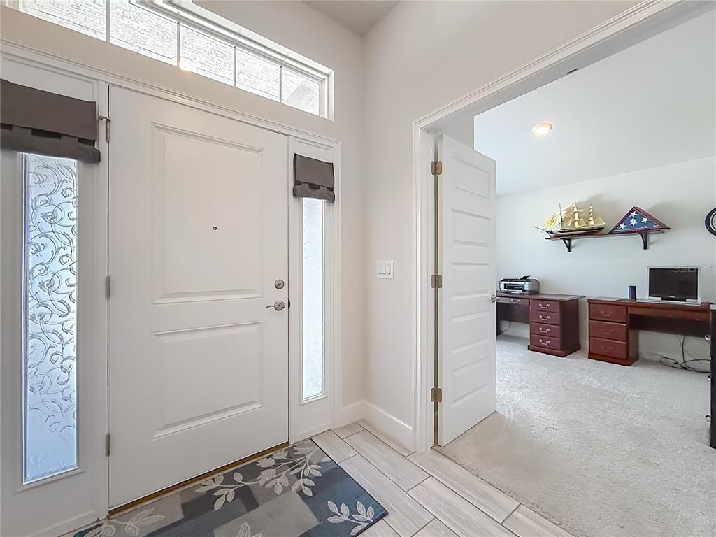 An entryway with a white front door leads to an adjacent room with a desk — 5578 CORAL REEF COURT, SPRING HILL, FL