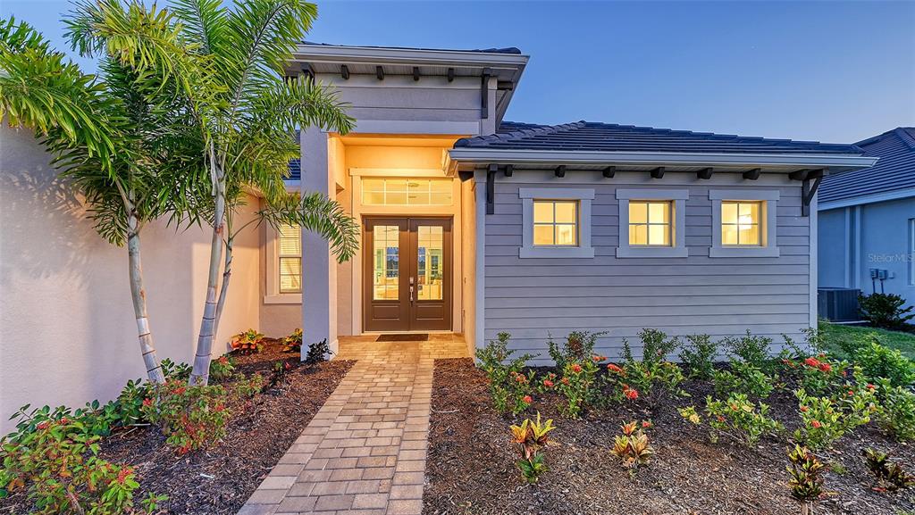 A single-story house exterior features gray horizontal siding, a stone walkway, and a palm tree — 12453 WELLEN GOLF STREET, VENICE, FL