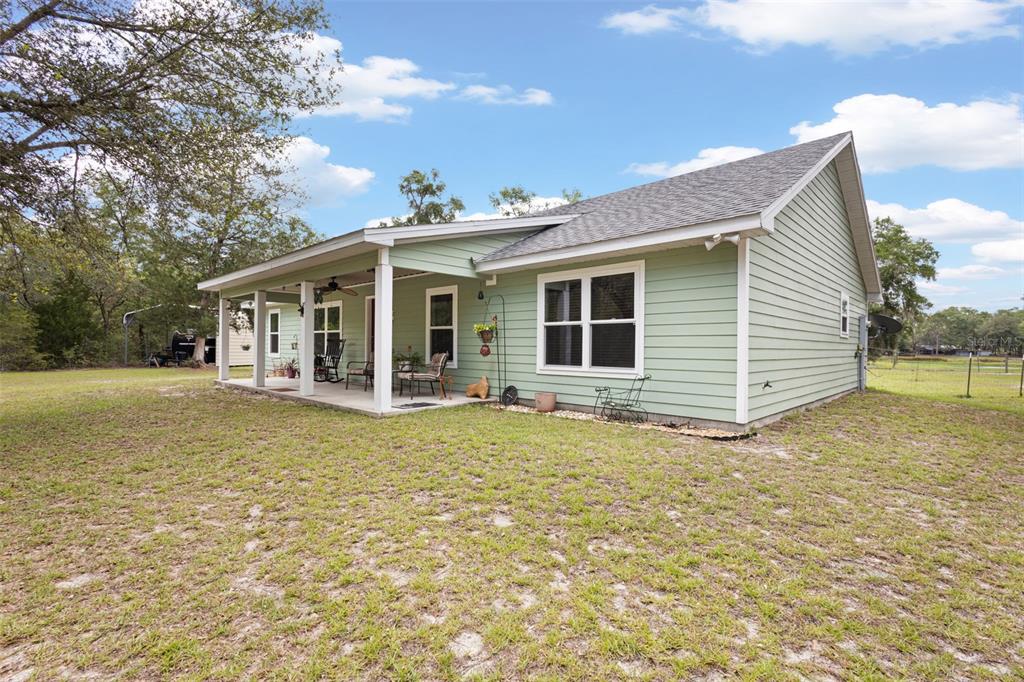 A light green house with a covered porch and a large grassy yard — 10250 NE 5TH AVENUE, BRANFORD, FL